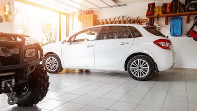 The interior of a home garage with a white SUV and an ATV parked inside